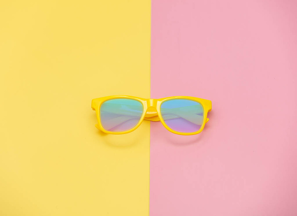Style sunglasses on pink and yellow backgrounds. Above view  - Photo, Image