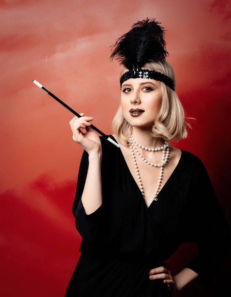 Красивая блондинка в 20 лет одежда с курительной трубкой на красном фоне
 - Фото, изображение
