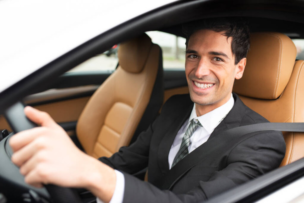 Smiling business man driving his new white car - 写真・画像