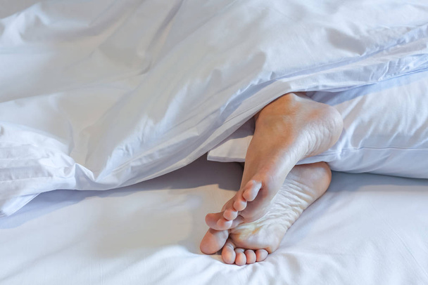 Feet of sleeping woman in white bed room - Фото, изображение