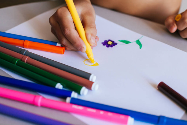 Criança que desenha um sol com marcadores coloridos fecham mãos
 - Foto, Imagem