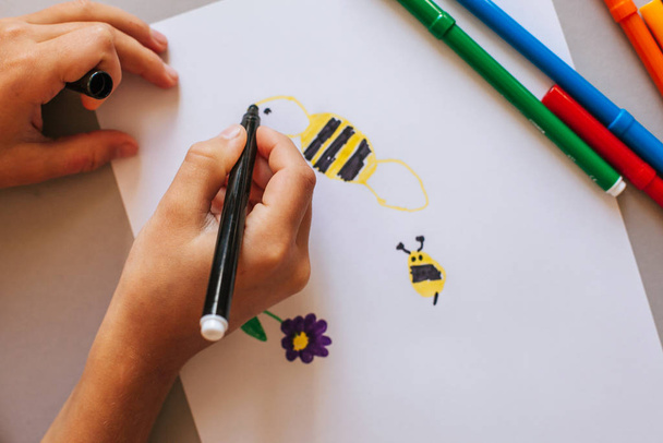 Criança que desenha um sol com marcadores coloridos fecham mãos
 - Foto, Imagem