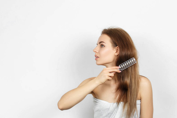 Beautiful woman in a towel combing hair. - Zdjęcie, obraz