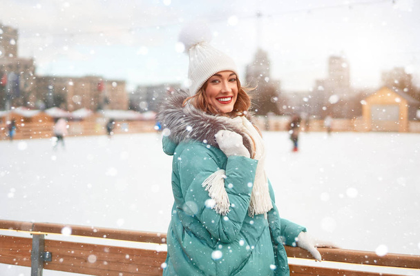 Gyönyörű szép középkorú lány göndör haj meleg téli kabátok áll jégpálya háttér város tér. - Fotó, kép