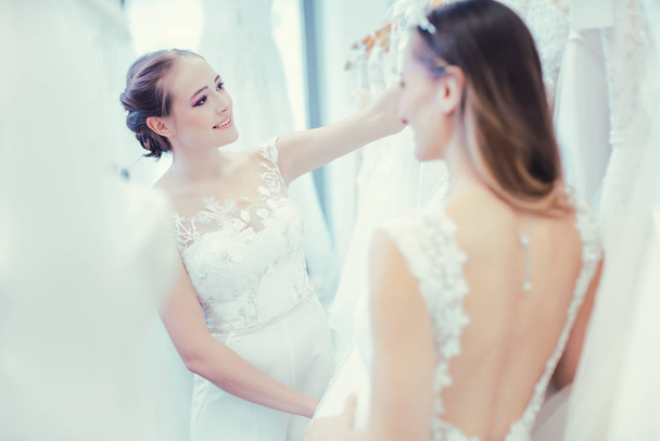 Two brides buying wedding dress in the store having fun - Фото, изображение