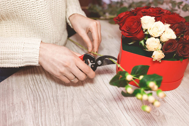 Flower shop seller prepares roses to create a bouquet by pruning them with pruners - Photo, Image