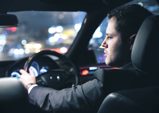 zakenman besturen van een auto in de nacht - Foto, afbeelding
