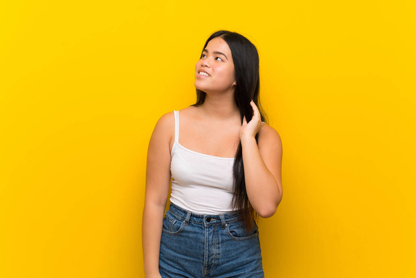 Joven adolescente asiática chica sobre aislado amarillo fondo pensamiento un idea
 - Foto, Imagen