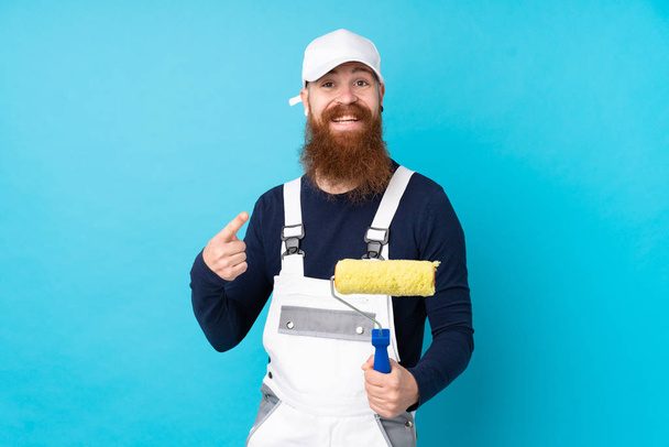 Художник с длинной бородой на изолированном синем фоне указывая пальцем в сторону - Фото, изображение