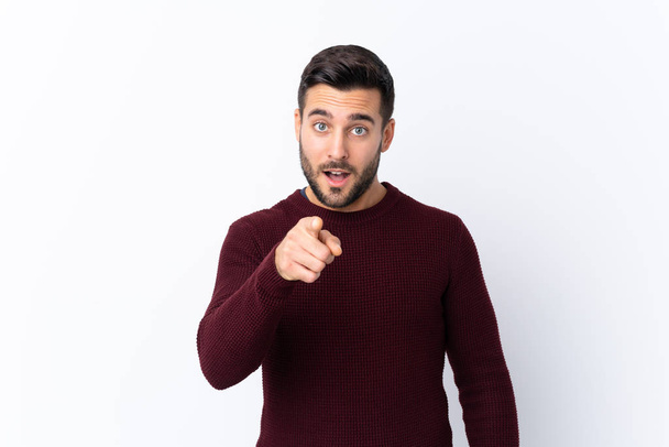 Young handsome man with beard over isolated white background surprised and pointing front - Zdjęcie, obraz