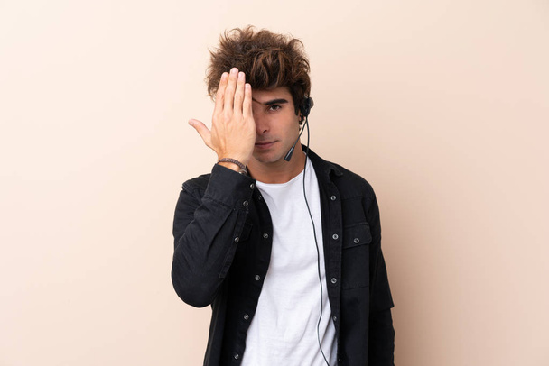 Hombre de telemarketer que trabaja con un auricular sobre un fondo aislado que cubre un ojo a mano
 - Foto, imagen