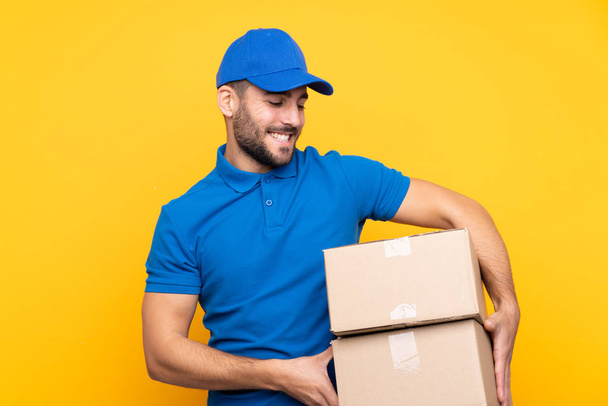 Delivery férfi felett elszigetelt sárga háttér boldog kifejezés - Fotó, kép