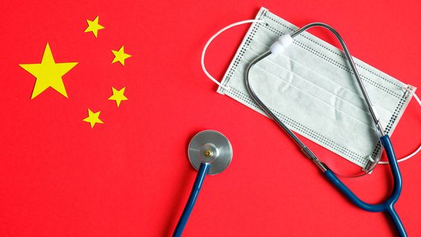 Novel Coronavirus prevention and treatment concept. Protective breathing mask and stethoscope over Chinese flag. Pandemic virus infection from Wuhan, China. 2019-nCoV Coronavirus outbreak. - 写真・画像