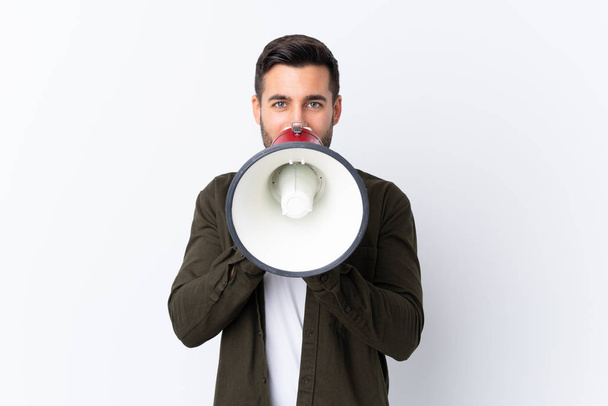 Молодий красивий чоловік з бородою над ізольованим білим тлом кричить через мегафон
 - Фото, зображення