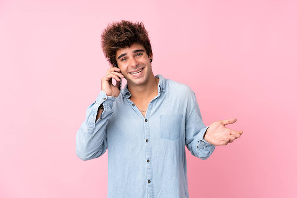 Jeune homme caucasien sur fond rose isolé gardant une conversation avec le téléphone portable avec quelqu'un
 - Photo, image