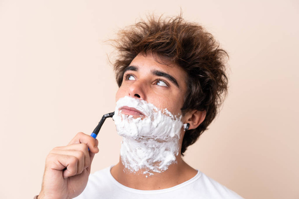 Νέος όμορφος άντρας ξυρίζει τα γένια του - Φωτογραφία, εικόνα