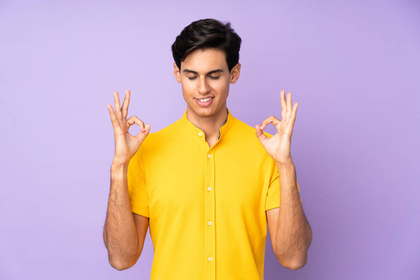 Man over isolated purple background in zen pose - Photo, Image