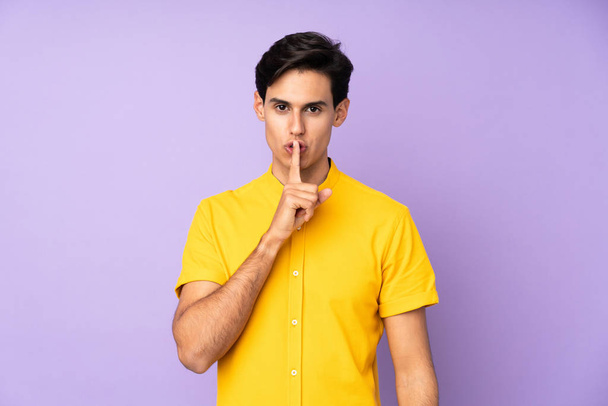 Man over isolated purple background showing a sign of silence gesture putting finger in mouth - Photo, Image