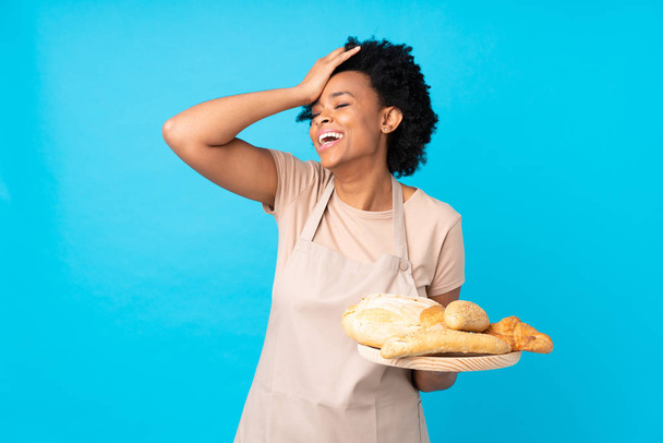 Afro-Amerikaanse vrouw in chef-kok uniform. Vrouwelijke bakker die een tafel houdt met meerdere broden heeft iets gerealiseerd en is van plan de oplossing - Foto, afbeelding