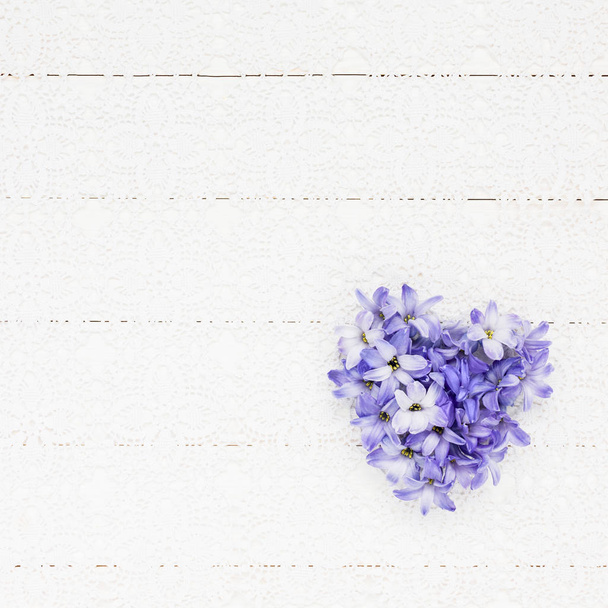 Herz aus Hyazinthenblüten auf einer weißen Spitzentischdecke. Valentinstag-Konzept. Ansicht von oben, Kopierraum - Foto, Bild