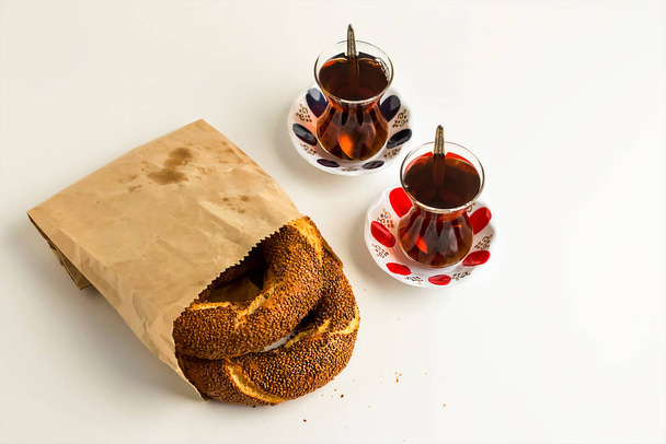 close-up shot of bagels covered with sesame seeds and glass cups of tea on white - Photo, Image