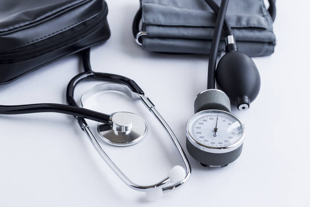 Medical equipments,stethoscope and blood pressure measuring tool (sphygmomanometer)on the white ground with leader bag. - Photo, image