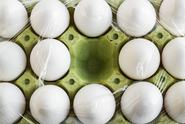 close-up shot of raw chicken eggs in carton on white surface - Foto, afbeelding