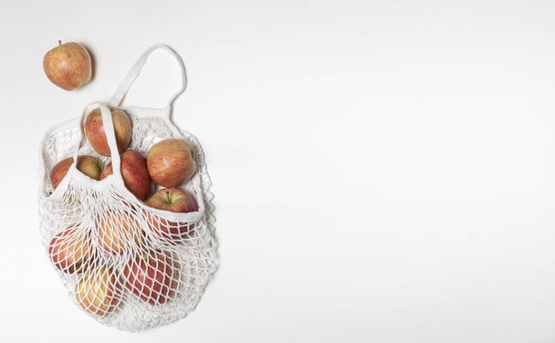 reusable Cotton String Portable Shopping Handbag with apples, white background, Fresh fruit, white string bag. Reusable zero waste textile bag, top view on white background.  - Zdjęcie, obraz