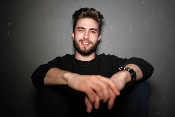 handsome young bearded man sitting on the floor   - 写真・画像