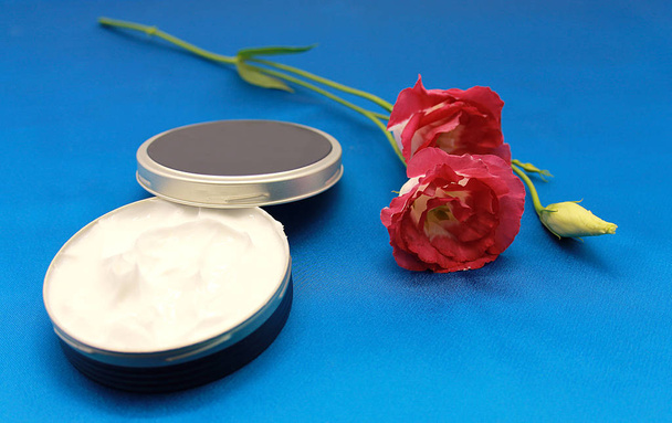 Crema facial natural y rosa japonesa sobre fondo azul
 - Foto, imagen