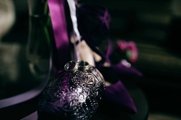 Vihkisormukset violetissa lasissa
  - Valokuva, kuva