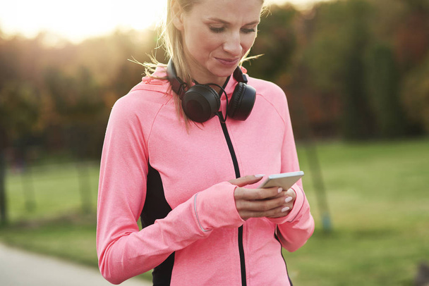 Sportlerin benutzt Handy beim Jogging-Training - Foto, Bild