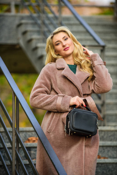 Feeling warm and protected. european winter. girl warm coat stairs background. faux fur coat fashion. stylish business lady leather bag. glamour girl look luxuriously. sexy blong woman. autumn season - Foto, afbeelding