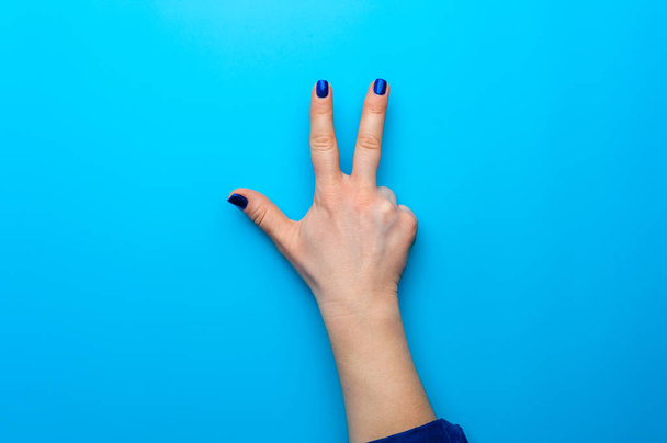Female hand with dark blue nails showing gesture - Fotoğraf, Görsel