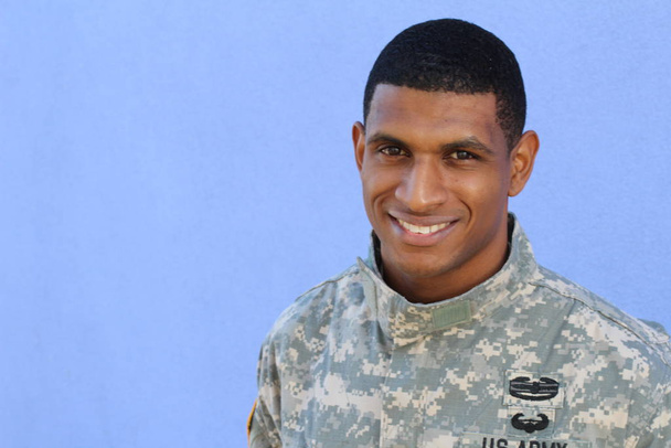 portrait en gros plan d'un beau jeune soldat afro-américain en uniforme devant un mur bleu
 - Photo, image