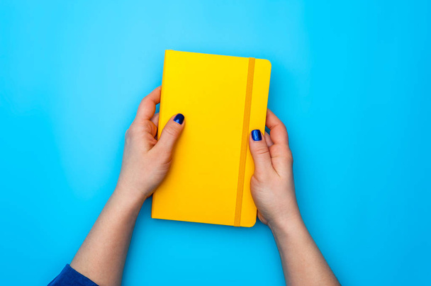 Beautiful female hands lie on a yellow diary - Foto, Imagem