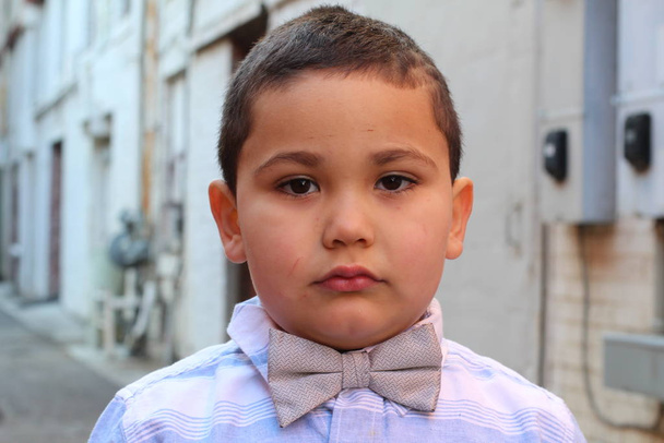 На відкритому повітрі портрет милого маленького хлопчика, який чує краватку
 - Фото, зображення