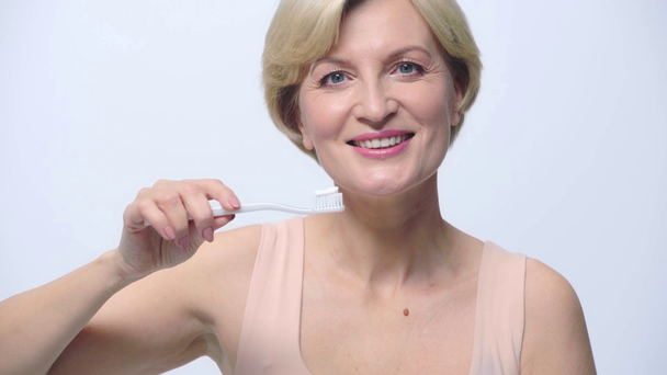 mulher madura segurando escova de dentes isolada no branco
  - Filmagem, Vídeo