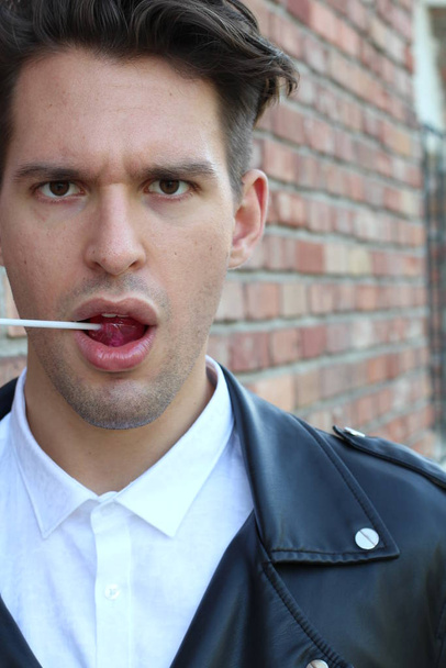 Silly man licks his lollipop in this funny childish photo - Photo, Image