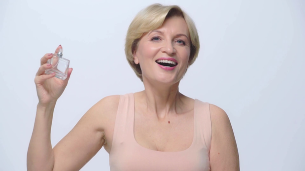 vrolijke vrouw spuiten parfum geïsoleerd op wit  - Video