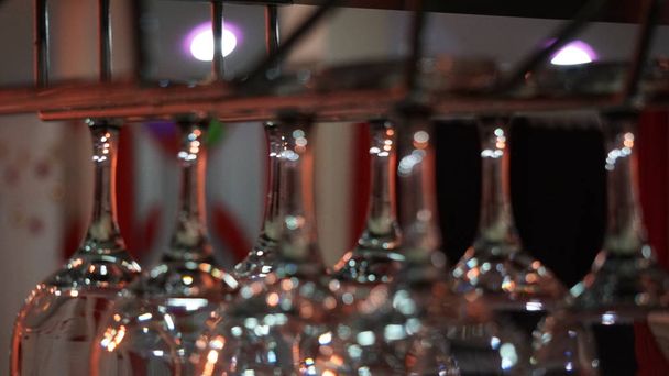 copas de vino cuelgan en un bar sobre un fondo de luces azules, rojas, azules y verdes que se reflejan maravillosamente en las copas
 - Foto, imagen