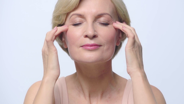 žena se zavřenýma očima dělá masáž obličeje izolované na bílém  - Záběry, video