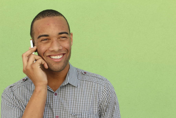 close-up portrait of handsome adult african american man talking by phone in front of green wall - Foto, Imagem