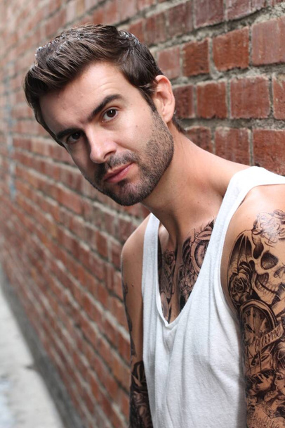 close-up shot of handsome young man with tattoos in casual clothes on street - Foto, Imagen