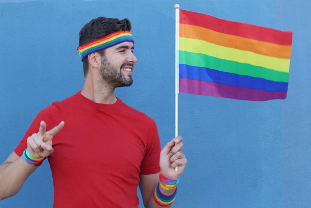 Красивый мужчина с гордостью держит флаг ЛГБТ
 - Фото, изображение