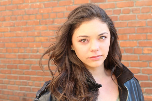Portrait of beautiful female teenager on brick wall background  - 写真・画像