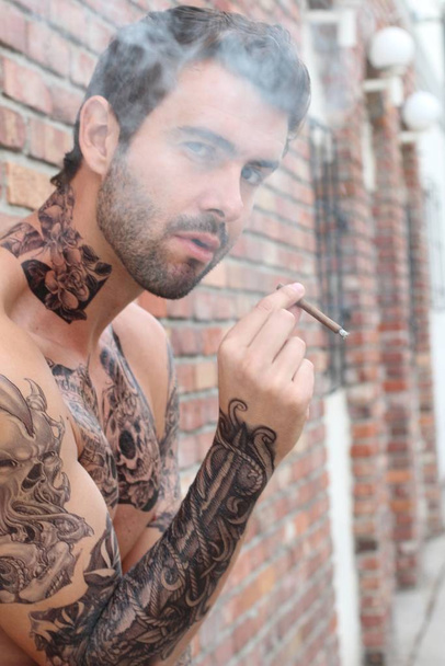 close-up shot van knappe jongeman met tattoos in casual kleding op straat - Foto, afbeelding