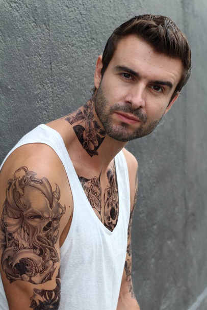 κοντινό πλάνο ενός όμορφου νεαρού άνδρα με τατουάζ σε καθημερινά ρούχα στο δρόμο - Φωτογραφία, εικόνα
