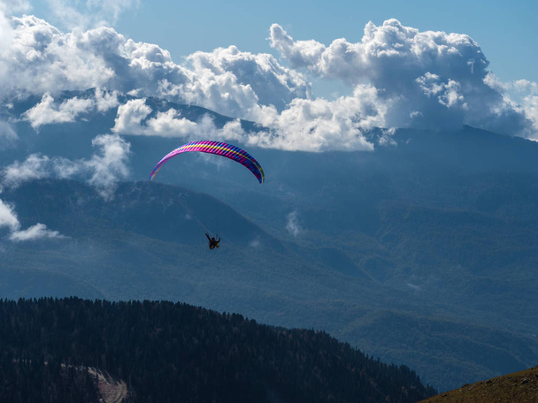 Parapendio vola sopra le nuvole sopra le montagne e sopra la foresta
 - Foto, immagini