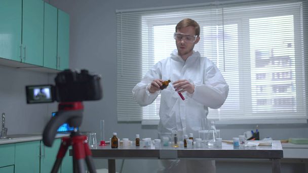 El hombre en ropa de trabajo protectora explica cómo trabajar con productos químicos en la cámara
  - Foto, Imagen